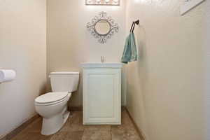 Bathroom with toilet, tile patterned flooring, baseboards, and a sink