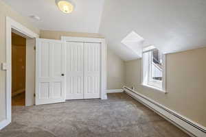 Additional living space featuring baseboard heating, carpet, lofted ceiling, and baseboards