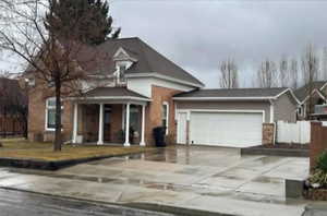 Traditional-style house featuring an attached garage, concrete driveway, and fence