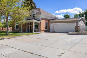 View of front of property featuring brick siding, concrete driveway, an attached garage, a porch, and a front lawn