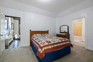 Bedroom with radiator heating unit, carpet flooring, baseboards, and ensuite bathroom