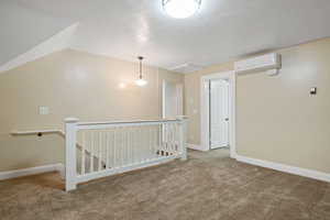Empty room featuring a wall mounted AC, carpet, and baseboards