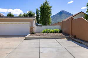 View of home's exterior featuring fence, a mountain view, stone siding, and a garage