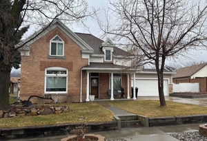 Traditional-style home featuring concrete driveway, a porch, a front yard, brick siding, and an attached garage