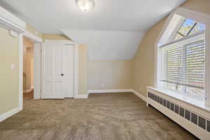 Bonus room with carpet flooring, vaulted ceiling, baseboards, radiator, and a baseboard heating unit
