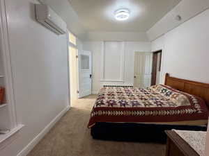 Bedroom featuring a wall mounted air conditioner and light colored carpet