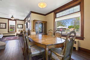 Dining room featuring radiator heating unit, dark wood-style floors, crown molding, a ceiling fan, and baseboards