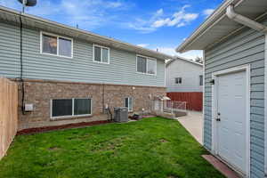 Back of house featuring brick siding, central air condition unit, and a patio