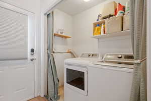 Clothes washing area with washing machine and clothes dryer and light wood-type flooring