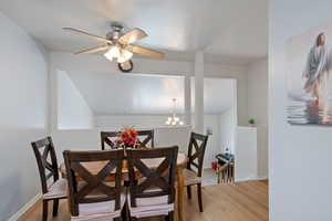Dining area with light wood finished floors, a chandelier, a ceiling fan, and baseboards