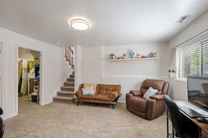 Living area featuring light carpet, stairs, and baseboards