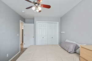 Carpeted bedroom featuring baseboards, a closet, and a ceiling fan