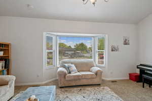 Carpeted living area featuring baseboards and a chandelier