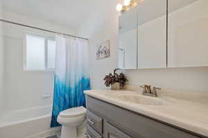 Bathroom featuring vanity, toilet, and shower / bath combination with curtain