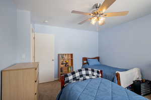 Carpeted bedroom featuring a ceiling fan and baseboards