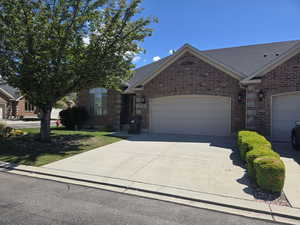 Ranch-style home featuring an attached garage, concrete driveway, brick siding, and a shingled roof