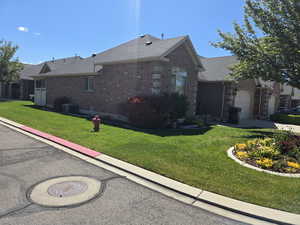 View of side of home with brick siding, a lawn, an attached garage, a shingled roof, and central AC unit