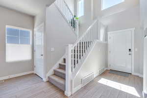 Foyer featuring stairway, LVP floors, and a high ceiling