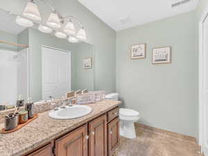 Full bath featuring toilet, vanity, a shower, a chandelier, and baseboards