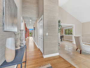 Corridor with baseboards, high vaulted ceiling, and light tile patterned flooring