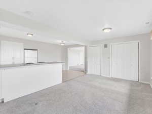 Unfurnished living room featuring light carpet and baseboards