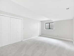 Unfurnished bedroom with light carpet, baseboards, and multiple closets
