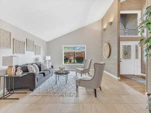Living area featuring baseboards, tile patterned flooring, and high vaulted ceiling