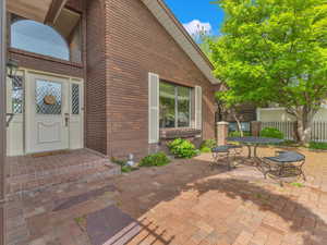 Entrance to property featuring fence, a patio area, and brick siding