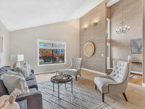 Living room with a chandelier, light tile patterned floors, baseboards, and high vaulted ceiling