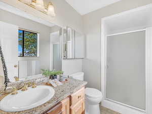 Bathroom with a stall shower, toilet, vanity, and tile patterned flooring