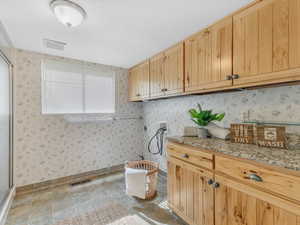 Laundry room with hookup for a washing machine, cabinet space, wallpapered walls, and baseboards