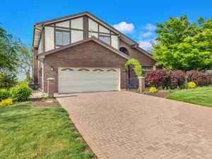 Tudor home with brick siding, decorative driveway, and a gate