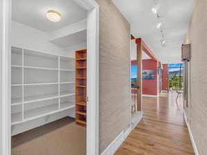 Hall featuring rail lighting and wood finished floors