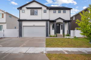 View of front of home with an attached garage, driveway, and a gate