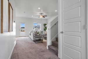 Carpeted living room featuring a ceiling fan, baseboards, recessed lighting, and stairs