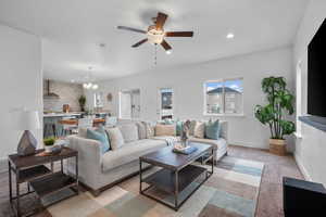 Living room featuring a chandelier, a ceiling fan, recessed lighting, light colored carpet, and baseboards