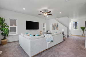 Carpeted living room with stairs, a ceiling fan, recessed lighting, and baseboards