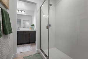 Bathroom with a shower stall, vanity, and tile patterned flooring