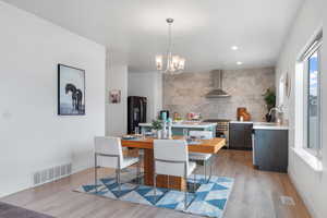 Kitchen featuring wall chimney range hood, high end stove, a sink, light countertops, and black fridge with ice dispenser