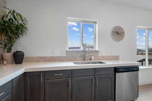 Kitchen featuring stainless steel dishwasher, a sink, light countertops, and light wood-style floors