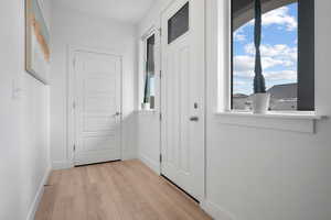 Doorway with light wood-style flooring, baseboards, and plenty of natural light