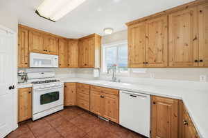 Kitchen featuring white appliances, a sink, and dark tile patterned floors