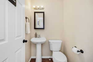 Half bath with toilet, baseboards, tile patterned floors, and a sink
