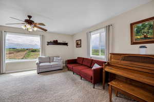 Living room with light colored carpet, healthy amount of natural light, ceiling fan, and baseboards