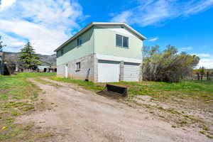 View of home's exterior with dirt driveway and a garage