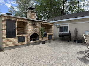 View of patio / terrace featuring an outdoor brick fireplace and area for grilling
