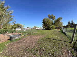 View of yard featuring fence, a vegetable garden, and a view of countryside horse pasture