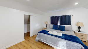 Bedroom with lofted ceiling, wood finished floors, baseboards, a closet, and recessed lighting