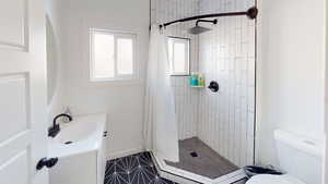 Full bathroom featuring a shower stall, toilet, vanity, tile patterned floors, and baseboards