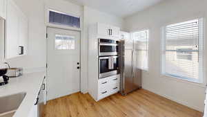Kitchen featuring stainless steel appliances, light wood-style flooring, white cabinetry, and a sink